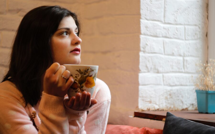 Una donna davanti la finestra con una tazza di tè
